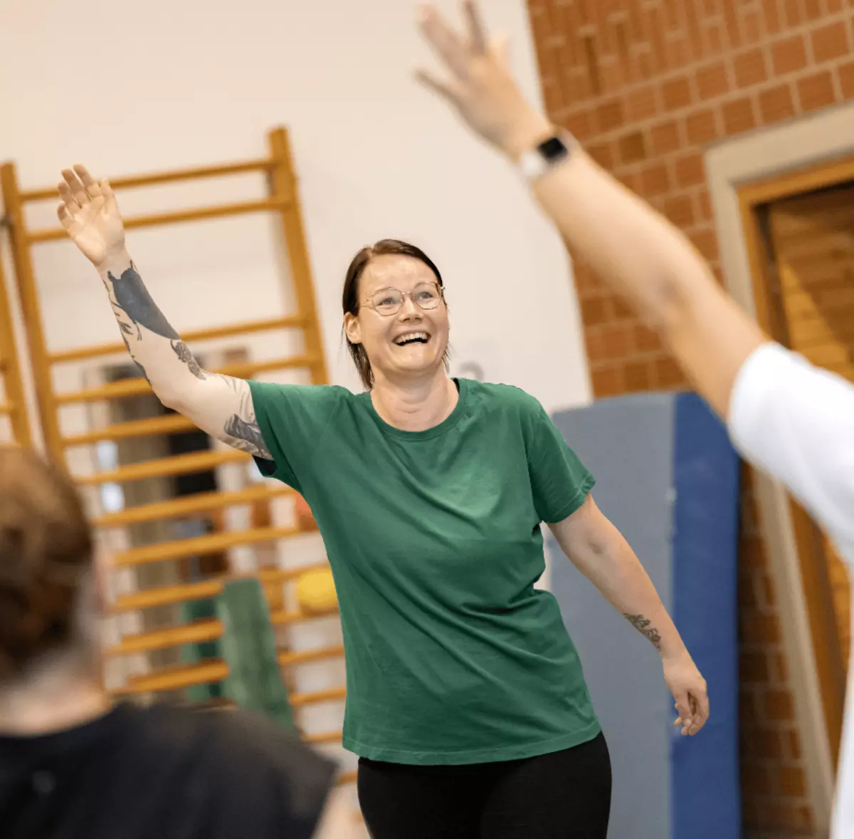 Lachende Frau hebt im Gruppentraining den Arm – aktive Reha für Gesundheit und Selbstständigkeit in der Dörenberg-Klinik.